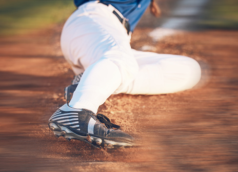 Slide, baseball action and athlete in a dirt for game or sports competition on pitch in stadium. Person, ground and  tournament performance by athlete or base runner in training, exercise or workout