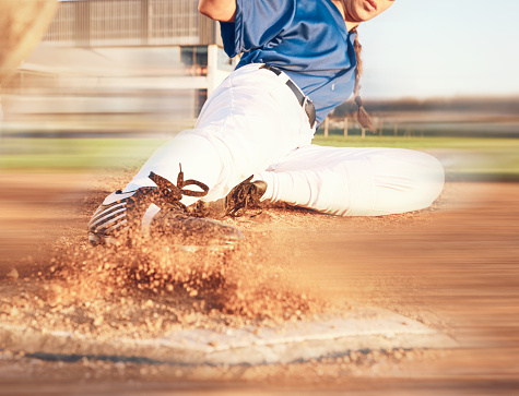 Slide, softball action and player in match or game for sports competition on a pitch in a stadium. Goal, ground and  tournament performance by athlete or base runner in training, exercise or workout