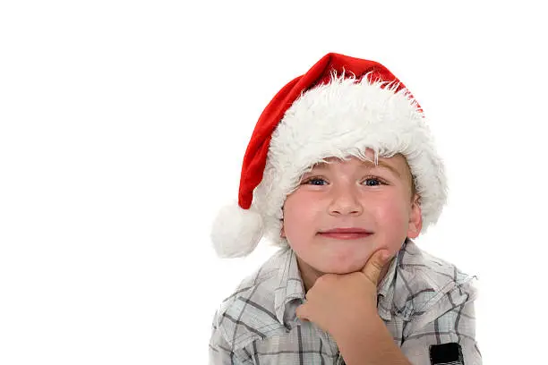 A little  five year old boy wearing a Christmas hat isolated on white with copy space.