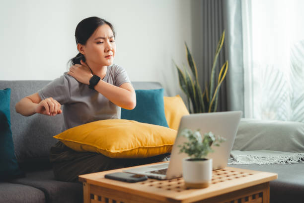 istock Asian woman using laptop suffering from body aching sitting on sofa at home. 1729756625