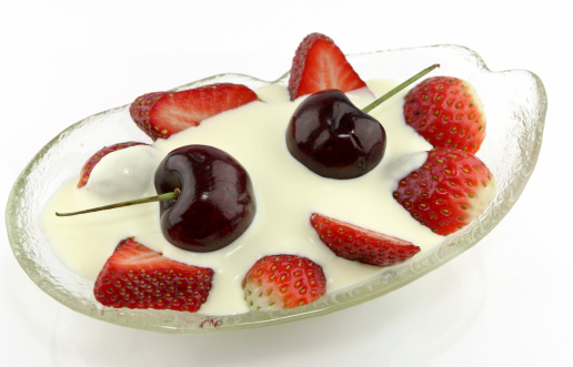 Rich desert of strawberrys cream and cherries in a glass bowl - white reflective background