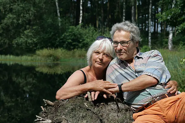 Photo of Happy Senior Couple sitting in front of a Pond