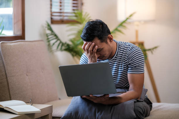 istock Unpleasant pain. Sad unhappy handsome man sitting on the sofa and holding his forehead while having headache 1729784536