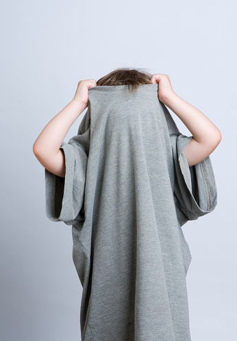 A young child hides in Daddy's t-shirt, pulling it up over his head.