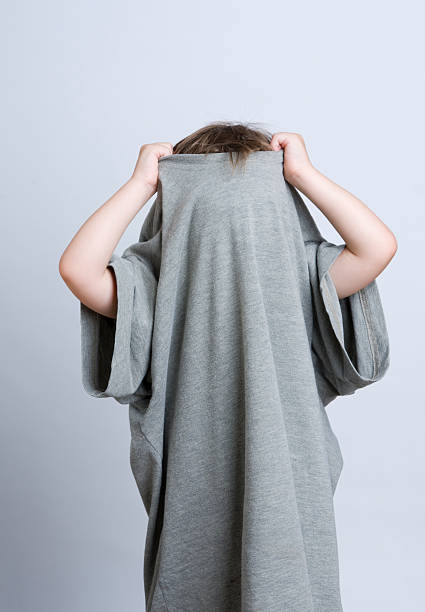 Young child hiding in Daddy's T-shirt A young child hides in Daddy's t-shirt, pulling it up over his head. too big stock pictures, royalty-free photos & images