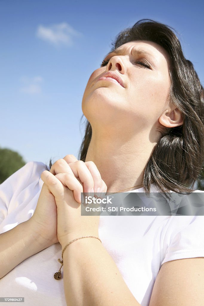 Young Woman Intensely Praying Looking Up To The Sky A young woman praying outside. 20-29 Years Stock Photo