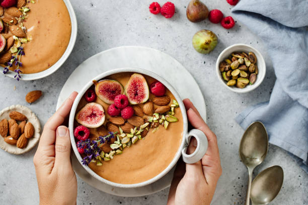 ドライフルーツとベリーを添えたスムージーボウルを持つ女性の手 - oatmeal porridge dried fruit bowl ストックフォトと画像