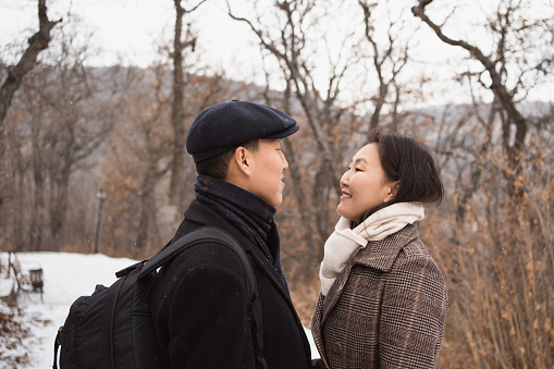 Asian couple in love looking to each other walking in winter park. Close up portrait