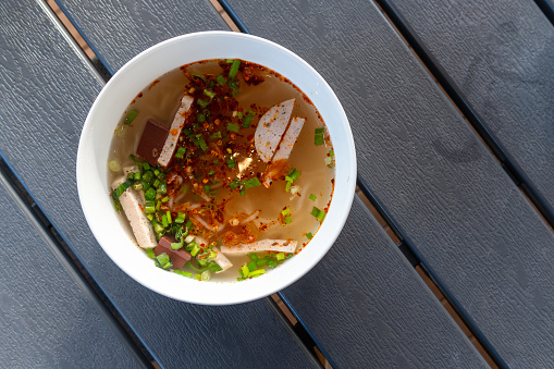 Boiled rice flour or Chinese pasta in a white bowl, placed on a wooden table. Chinese or Vietnamese food, breakfast, restaurant along the Mekong River, Nakhon Phanom Province, Thailand.