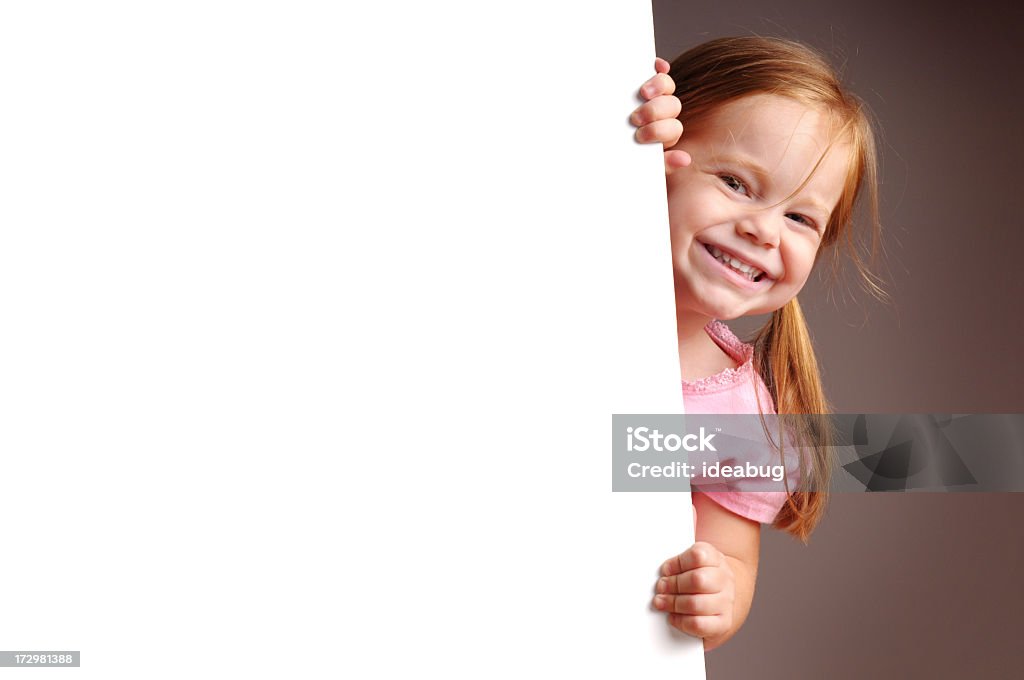 Fillette heureuse regarder derrière un panneau vierge - Photo de Enfant libre de droits