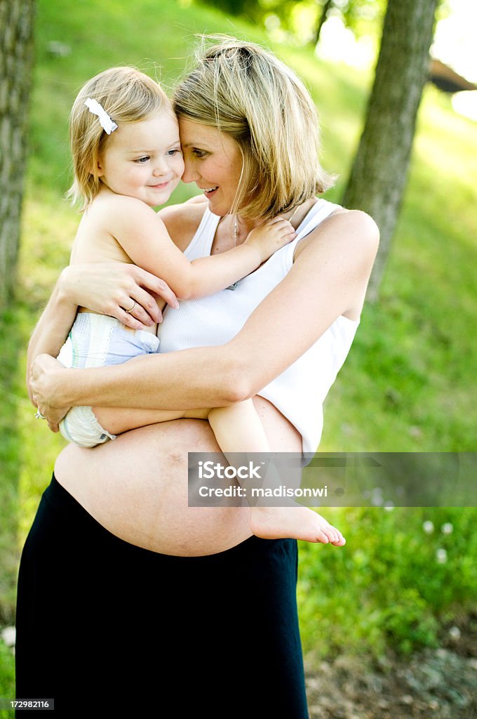 Pregnant mother Beautiful pregnant woman holding her daughter on her belly. 12-17 Months Stock Photo