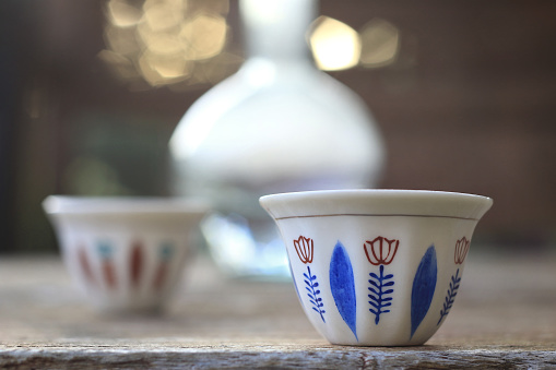 Two Lebanese traditional coffee cups along with a glass water jug, ebrik.