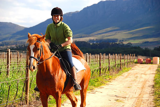 Shot of a young woman riding a horse on a farm