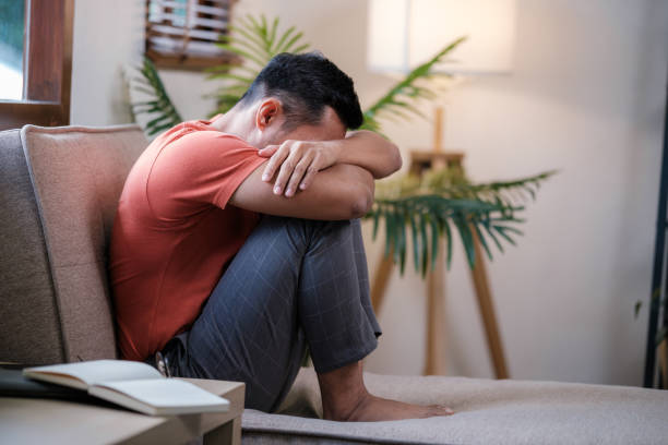 istock Unpleasant pain. Sad unhappy handsome man sitting on the sofa and holding his forehead while having headache 1729823461