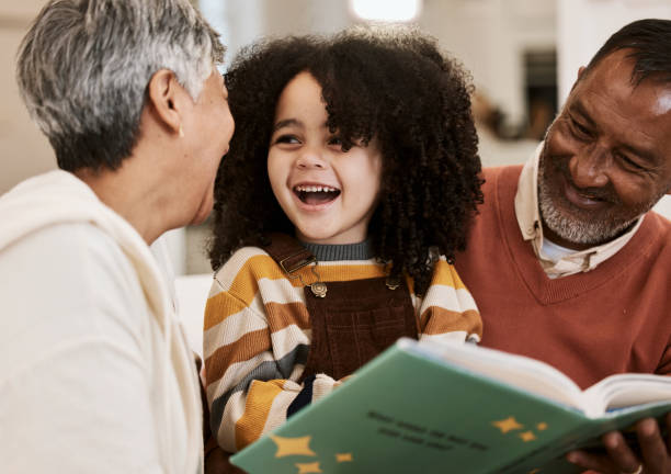istock Grandparents, kid and happy for reading, book or home for support, learning or education with laugh. Senior man, woman and young child for funny story, teaching or help for development in family home 1729824000