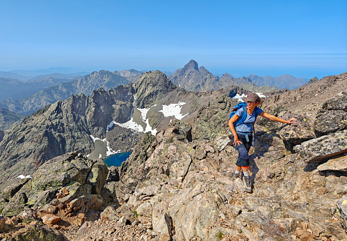 Corse, France - 27 June 2023 - Corsica is a big marine french island in Mediterranean Sea, with hights mountains. Here a view Monte Cinto peak of island, 2706 meters, with the famous GR20 path and girl alpinist in the peak