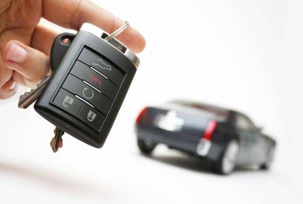 Car keys in a hand with an unfocused car in the background stock photo
