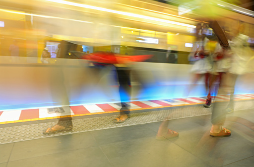 intentionally blurred motion effect of subway traveling fast in station with people walking