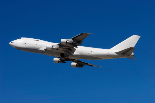 A large cargo airplane in flight against a clear blue sky.