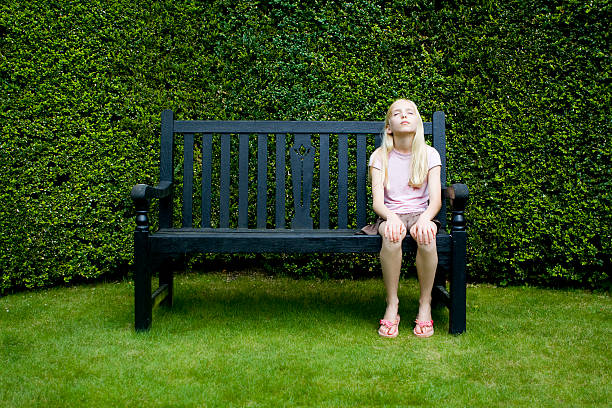 Happy family moments in the city. Photo portrait of little girl wearing red beret and coat sits at bench at city street outdoors.