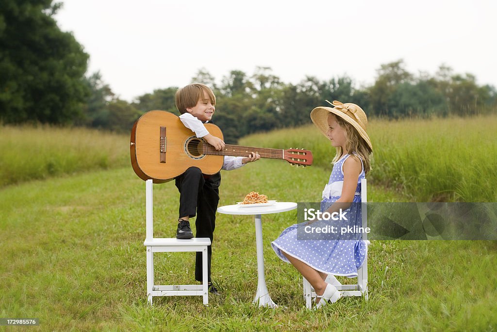 Petit garçon avec la guitare serenades fille assis à table - Photo de Guitare libre de droits