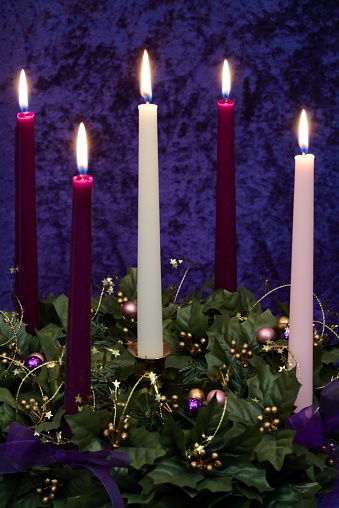5 candle Advent wreath with 3 purple, 1 pink, 1 white candles arranged on decorated wreath. Vertical image would be good for Christian or religious Christmas use.