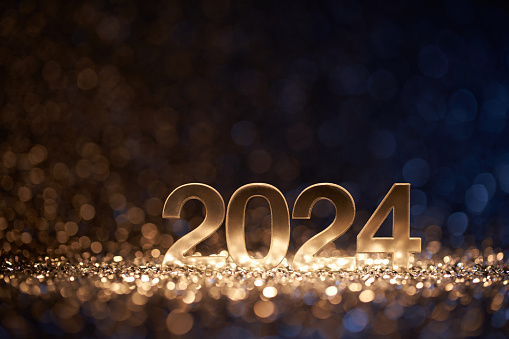 Low key photography of the golden number 2024 surrounded by blue and gold sparkling defocused lights. Native image size: 7952x5304