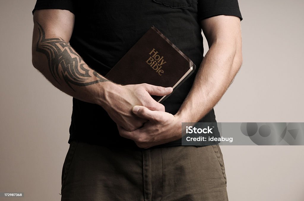 Christian Grunge Grungy, desaturated images of a young man with tattooed arm holding a bible. Adult Stock Photo