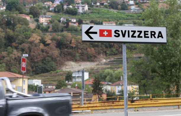 road sign with the text svizzera in italian which means swiss confederation and the arrow - helvetic imagens e fotografias de stock