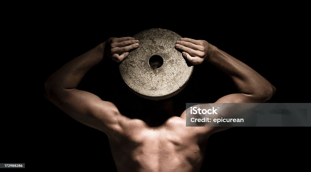 Muscolo testa muscoloso uomo che tiene un peso superiore a faccia - Foto stock royalty-free di Arto - Parte del corpo