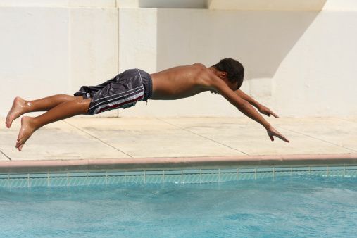 Boy child swimmer dive into swimming pool. Young male athlete diving into water pool. Water sports, training, competition, activities, learning to swim school classes for children