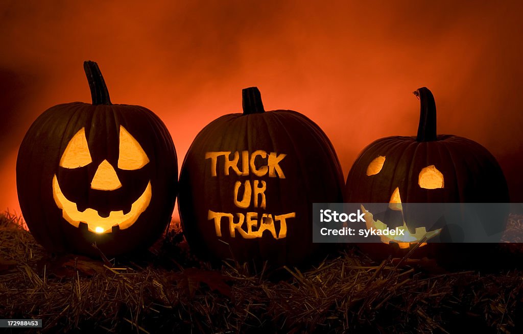 Have Fun Trick Or Treating Three Jack O Lanterns illuminated with orange / redish fog in the background. Two faces and a Trick or Treat. Trick Or Treat Stock Photo