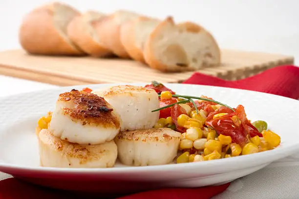 Pan-seared New England bay scallops served with a hash of tomato, corn and edamame.