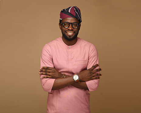 portrait Working African man wearing Pink attire, confident, Crossed hands looking at the camera with confidence and a toothy smile