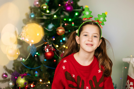 Christmas portrait of a teenage girl on the background of a Christmas tree, bokeh.