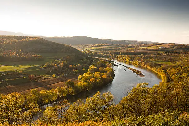 River runs through a farmland valley as the leaves change