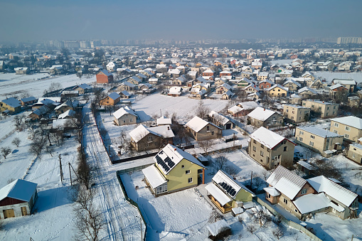 Aerial view of private homes with snow covered roofs in rural suburbs town area in cold winter.