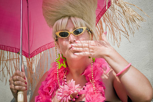 Baltimore Hon Blows a Kiss Hon Fest. Hampden. Baltimore, Maryland. Woman on street role-playing the city's traditional retro hon festival. She carries hot pink accessories, wears multi-colored sparkling sunglasses and blows a kiss to her admiring crowd. A fringed pink parasol protects her from the hot, noontime sun.  beehive photos stock pictures, royalty-free photos & images