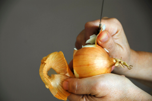 2 hands peeling an onion