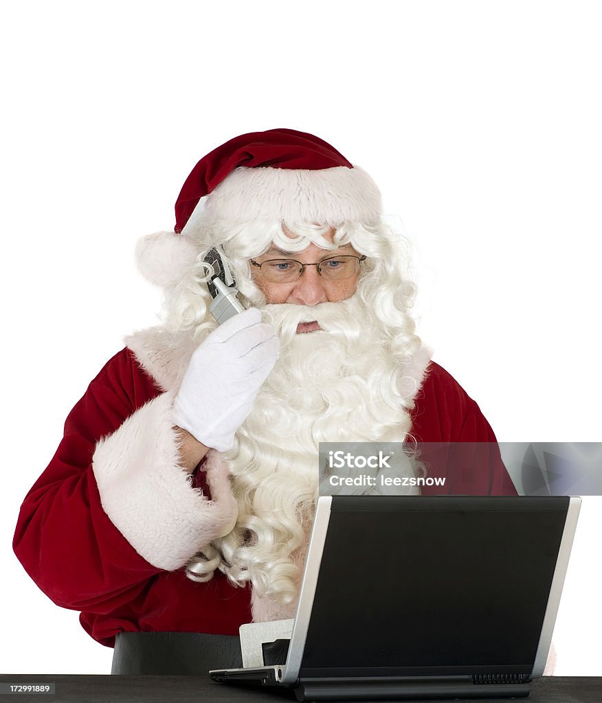 Santa On Phone With Laptop High tech Santa taking orders on his cell phone and placing orders online. Christmas Stock Photo