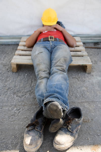 Worker is sleeping Sun is coming from foot side: Work time for the worker lazy construction laborer stock pictures, royalty-free photos & images