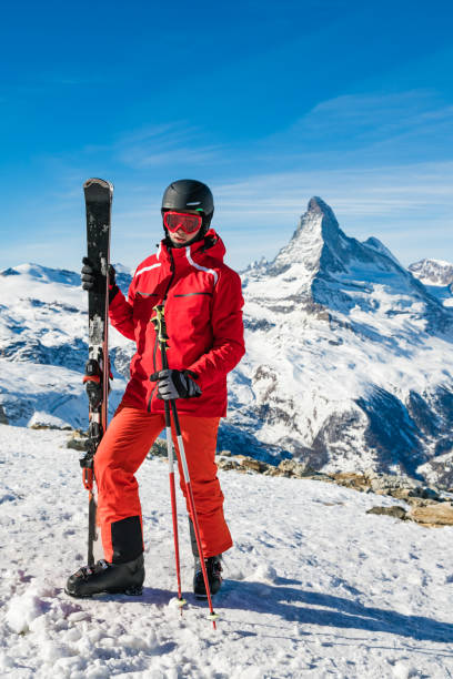 Young skier holding skis against Matterhorn mountain, Switzerland Young skier holding skis against Matterhorn mountain, Valais canton, Switzerland, in winter morning. Taken by Sony a7R II, 42 Mpix. switzerland european alps ski winter stock pictures, royalty-free photos & images