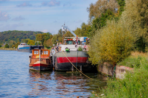 istock Two boats anchored at a dock berth on Albert Canal, cargo ship in background 1729930419
