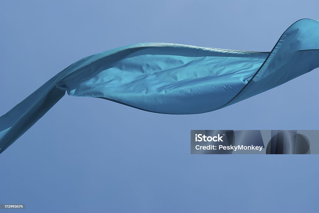 Ribbon of Shiny Blue Fabric in the Sky Ribbon of shiny blue fabric floats in the wind against a sunny blue sky Ribbon - Sewing Item Stock Photo