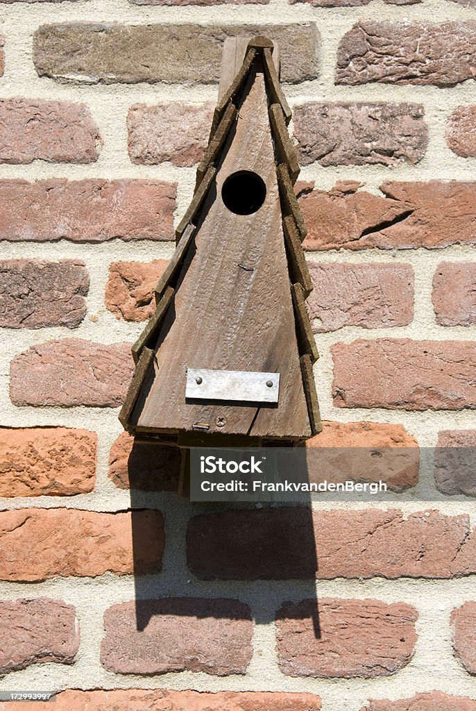 Triangle birdhouse Triangle birdhouse hanging on a brick wall. With empty nameplate.Other images; Animal Stock Photo
