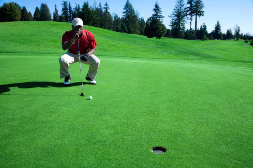 Photo of a golfer crouching to line up a putt.