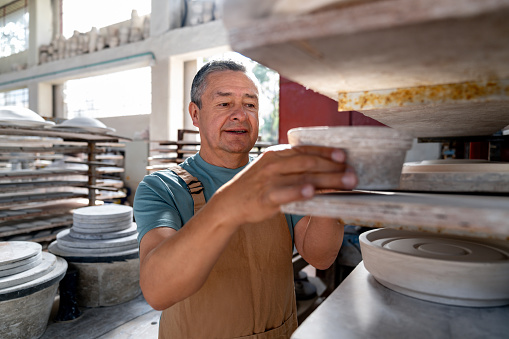 Latin American man working at a pottery factory doing quality control - manufacturing concepts