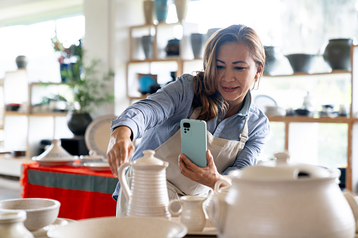 Business owner taking photos of her products at a pottery shop