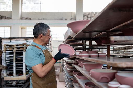 Latin American employee doing quality control while working at a ceramics factory - manufacturing concepts