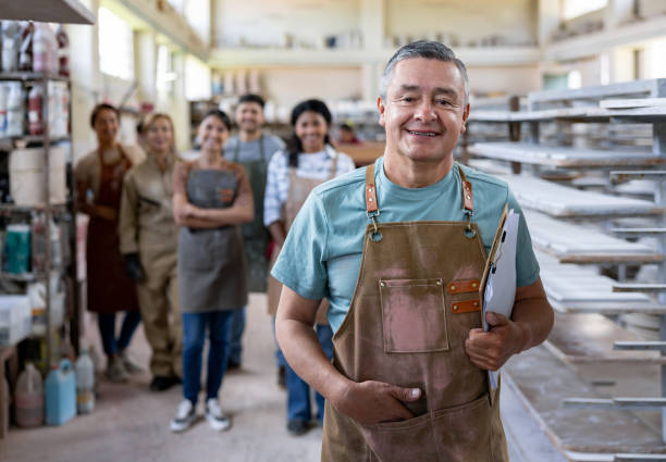 istock Manager working at a ceramics factory leading a group of workers 1729966359